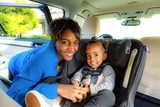 Mother placing child in car seat