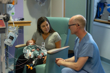 Mother holds her baby while chatting with staff