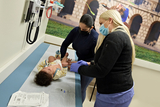 A baby is examined by a doctor and mom assists