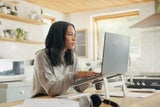 Concerned mother looking for resources sitting at laptop in kitchen