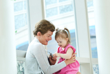 Doctor and toddler in pink dress, sitting in a hallway