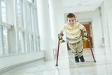 Happy boy patient walking with crutches in corridor at hospital.