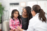 Little girl patient listening to doctor and sitting with mother.