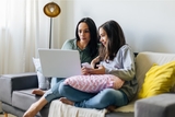 Mom and teen daughter looking at laptop researching for resources.