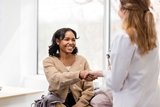 Older girl smiling and  shaking hands with female doctor in white coat.