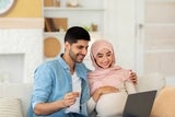 Husband with pregnant wife using a laptop