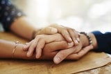 Comforting adult hands holding a teens hand