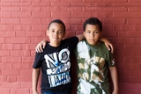 Two boys standing against a brick wall