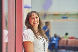 Staff member in white shirt leaning on a red wall