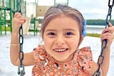 Lilliana smiling while riding a swing