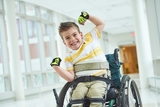 Smiling boy in wheelchair wearing green gloves