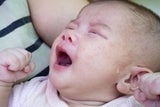 Crying baby with hands clinched