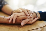 Comforting adult hands holding a teens hand