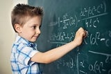 Boy writing equations on chalkboard