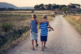 Two boys walking on dirt road