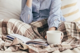 Person sitting in bed and holding a mug