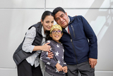 Family smiling in front of a white wall