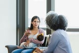 Woman holds baby and talks with another woman.