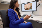 Young female doctor reviews images of skin issues from patients via a digital appointment