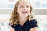 Blonde freckled girl sitting by the window and smiling