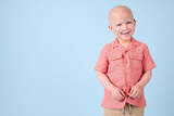 Smiling young boy in front of a light blue backdrop