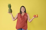 Food Pharmacy employee holding fruit and smiling.