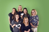 A group of oncology staff holding heart symbols and smiling.