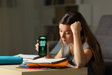 Young girl studying drinking an energy drink