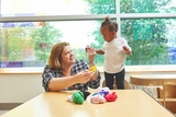 Employee with a toodler at a table with toys.