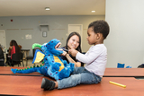 HHI patient learning to use a toothbrush on a stuffed dinosaur.