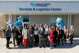 A group of employees posing for a photo in front of of CHOP building.