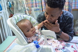 Father kissing hand of his newborn with a tracheotomy