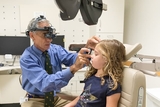 Doctor checking patient's eye in exam room