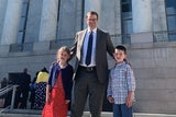 Father standing outside a courthouse with his children