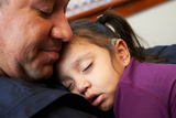 father holding sleeping daughter