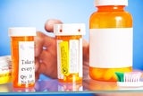 Hand reaching into medicine cabinet with pill bottles