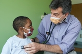 Doctor listening to young boy's heartbeat