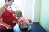 Child kissing mom's pregnant belly