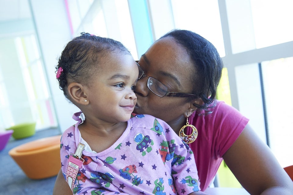 Mother kissing cheek of daughter in hospital gown