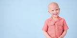 Smiling young boy in front of a light blue backdrop