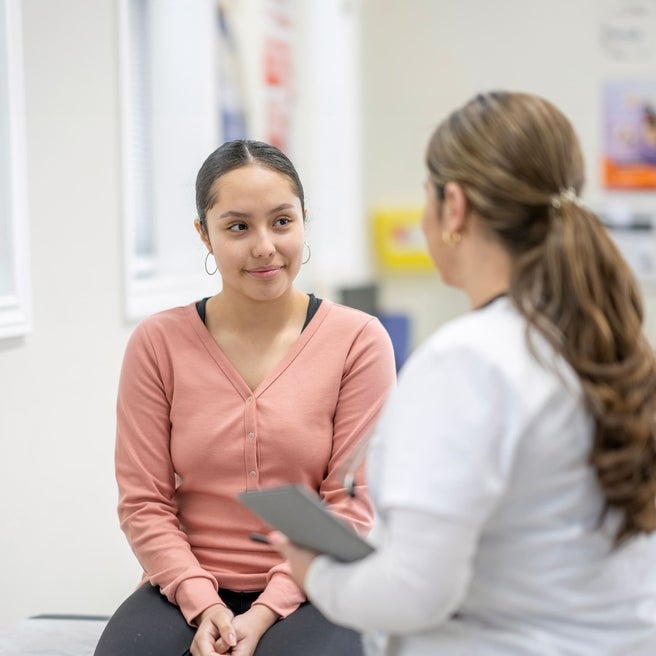 teenage girl facing doctor in an office