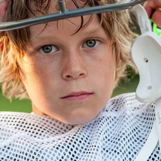 Young Boy taking his football helmet off looking concerned