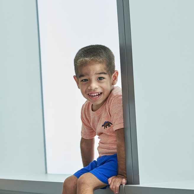 Young boy sitting on window ledge smiling