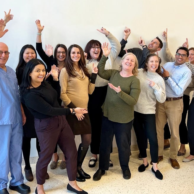 Group of physicians smiling and pointing at the ceiling.