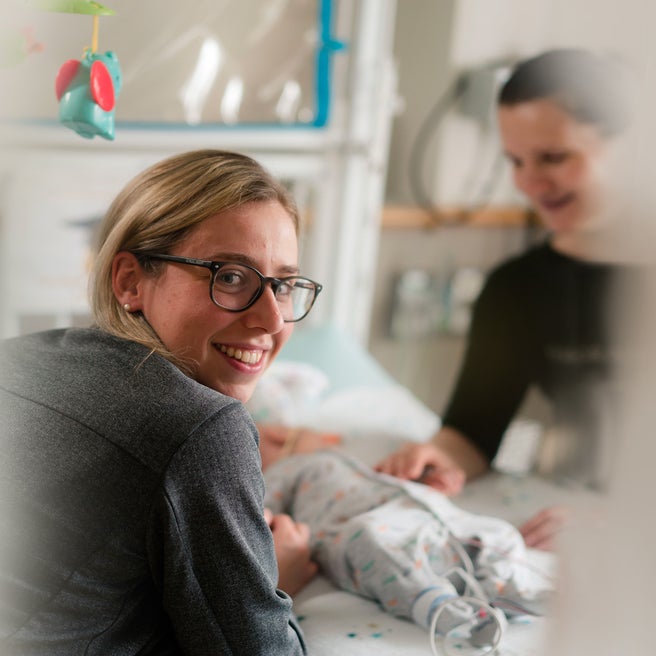 Smiling staff member stops by a patient's bedside