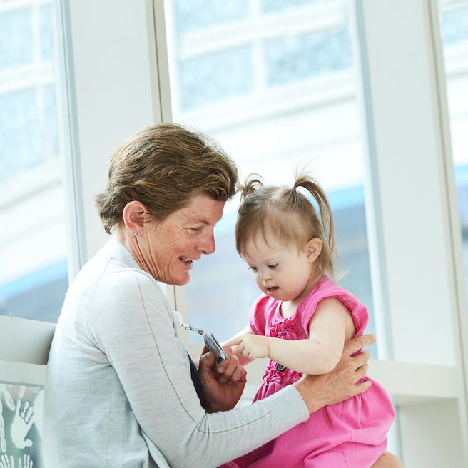 Doctor and toddler in pink dress, sitting in a hallway