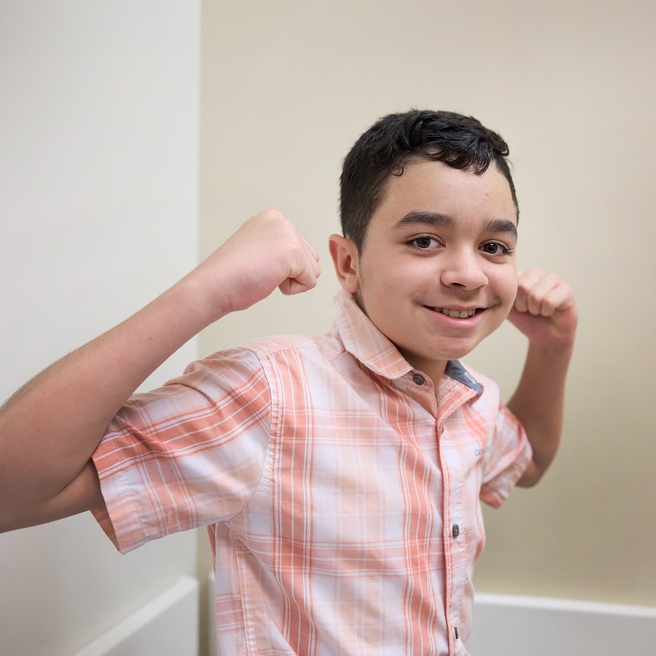 Tween boy flexing muscles looking strong sitting in Neurologist doctor office.