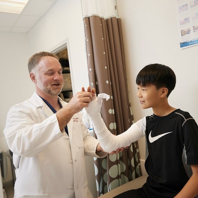 Boy with his doctor discussing a broken arm in a cast.