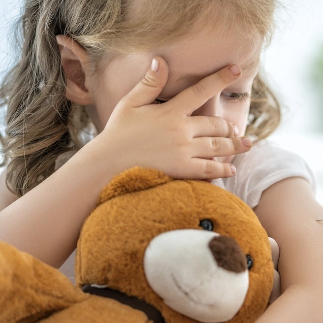 Girl peeking through fingers at needle