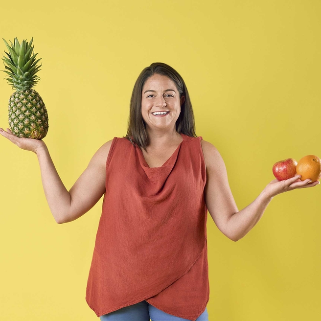 Food Pharmacy employee holding fruit and smiling.